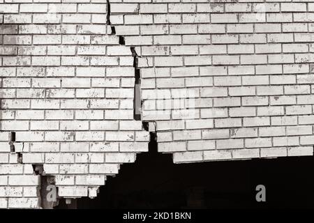 Building exterior brick wall with extreme damage cracks holding up from vehicle collision.Sepia black and white photo abstract background photo. Stock Photo