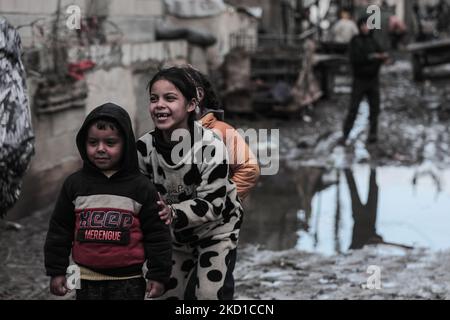 Palestinian children living in slums play in the street during cold weather in a slum in Gaza City, Thursday, January 27, 2022.(Photo by Momen Faiz/NurPhoto) Stock Photo