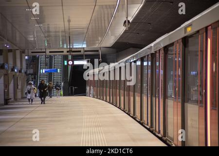 A metro stop at the center of Amsterdam with the train carriage on the right and a few people walking. Daily life during the lockdown at the fourth wave of the pandemic. Locals and a few tourists at the quiet streets of Amsterdam during the lockdown in the Dutch capital city with stores and shops appearing with closed with the roller metal shutter down, cafes, bars and restaurants also closed with tables and chairs of the terraces locked. The Netherlands was the first European nation to declare full lockdown to fight the new Omicron variant that surges. After a sudden government order before C Stock Photo