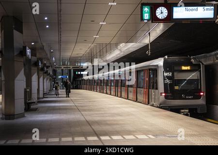 A metro stop at the center of Amsterdam with the train carriage on the right and a few people walking. Daily life during the lockdown at the fourth wave of the pandemic. Locals and a few tourists at the quiet streets of Amsterdam during the lockdown in the Dutch capital city with stores and shops appearing with closed with the roller metal shutter down, cafes, bars and restaurants also closed with tables and chairs of the terraces locked. The Netherlands was the first European nation to declare full lockdown to fight the new Omicron variant that surges. After a sudden government order before C Stock Photo