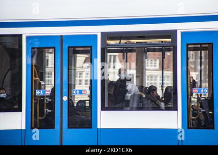 People are spotted in the tramway wearing facemask.Tram in Amsterdam is part of the public transportation system GVB. Daily life during the lockdown at the fourth wave of the pandemic. Locals and a few tourists at the quiet streets of Amsterdam during the lockdown in the Dutch capital city with stores and shops appearing with closed with the roller metal shutter down, cafes, bars and restaurants also closed with tables and chairs of the terraces locked. The Netherlands was the first European nation to declare full lockdown to fight the new Omicron variant that surges. After a sudden government Stock Photo