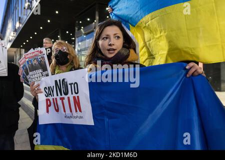 LONDON, UNITED KINGDOM - JANUARY 31, 2022: Protesters hold Ukrainian flags as they demonstrate outside the studios of RT, Russian state-owned international television network, against Russia's military build-up on the border with Ukraine amid rising tensions between East and West on January 31, 2022 in London, England. An estimated 100,000 Russian troops, tanks, artillery and missiles are deployed near the border with Ukraine but the Kremlin denies invasion plans while making demands from NATO last month that Ukraine and other ex-Soviet countries are denied its membership and withdrawal of all Stock Photo