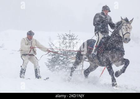 Competitors wearing traditional folk costumes take part in Kumoterki racing in Bialy Dunajec, Poland on January 30, 2022. Traditional races called Kumoterki take place in Tatra mountains every winter. The event consists of sleigh racing, being dragged on skis by a horse while another competitor is riding it, and skiring, a sport in which skiers are pulled along by a free-running horse. (Photo by Beata Zawrzel/NurPhoto) Stock Photo