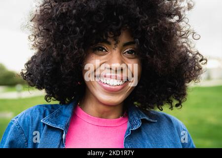 Happy African American woman having fun looking in front of a camera in public park Stock Photo