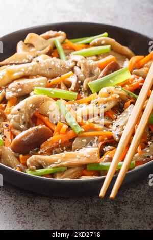 Stir-fried oyster and shiitake mushrooms with carrots, sesame seeds and green onions closeup in the plate on the table. Vertical Stock Photo
