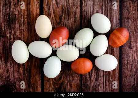 Blue, Green, and Brown Heritage Eggs On a Rustic Wood Background: Overhead view of a group of a dozen multicolored eggs on a wooden table Stock Photo