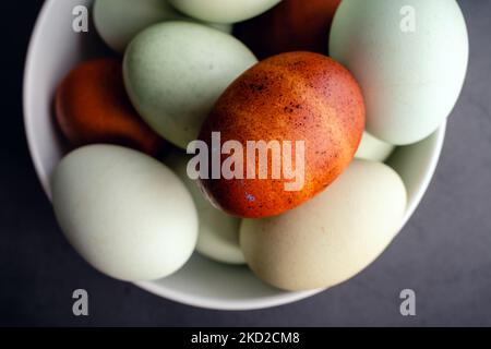 Blue, Green, and Brown Heritage Eggs In an Bowl On a Rustic Wood Background: Overhead view of a group of multicolored eggs on a wooden table Stock Photo