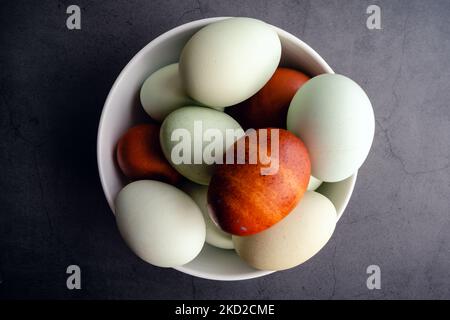 Blue, Green, and Brown Heritage Eggs In an Bowl On a Rustic Wood Background: Overhead view of a group of multicolored eggs on a wooden table Stock Photo