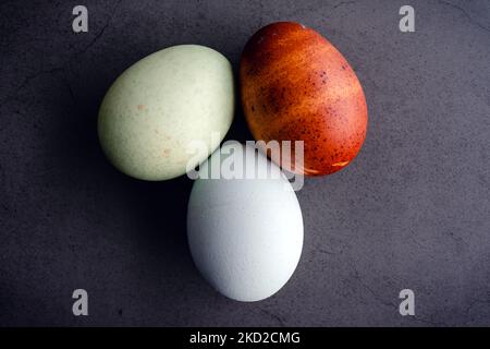 Blue, Green, and Brown Heritage Eggs On a Dark Background: Overhead view of a group of three colorful heritage eggs eggs Stock Photo