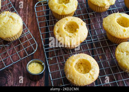 Cored Vanilla Cupcakes on a Wire Cooling Rack: Vanilla cupcakes with their centers removed for filling Stock Photo