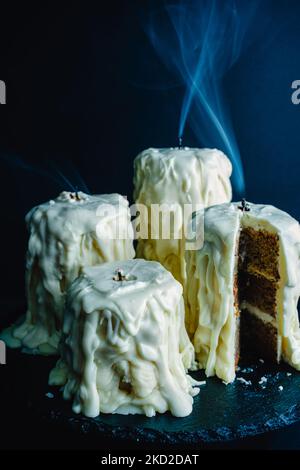 Melted Candle Cakes with Streams of Smoke: Cakes made to look like blown out candles on a dark black background Stock Photo