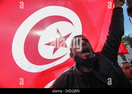 A supporter of the Islamist-inspired party Ennahda shouts slogans next to a giant Tunisian flag during a demonstration held at the initiative of “Citizens Against the Coup - the Democratic Initiative” campaign, on Mohamed 5 avenue in the capital Tunis, Tunisia, on February 13, 2022, to protest against the dissolution of the country’s Supreme Judicial Council and called for the independence of the judiciary. Protesters also called for the release of the Vice President of Ennahda party, Noureddine Bhiri who is placed under house arrest since more than six weeks. Demonstrators also protested agai Stock Photo