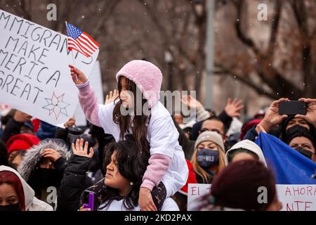 A young girl waves a tiny American flag while sitting on someone's shoulders during a Day Without Immigrants rally at the White House. The rally is part of a nationwide day of action and protest during which organizers have asked immigrants not to go to work and school, or to spend money. Their goal is to demonstrate the degree to which the US depends on immigrants and pressure the Biden Administration and Congress to create a pathway to permanent residency and citizenship for the 11 million undocumented workers in the United States. (Photo by Allison Bailey/NurPhoto) Stock Photo