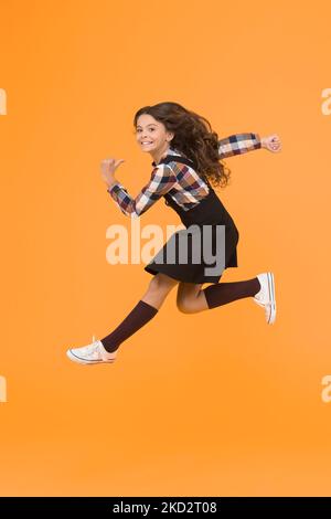 Break into. Feel inner energy. Girl with long hair jumping on yellow background. Carefree kid summer holiday. Time for fun. Active girl feel freedom Stock Photo