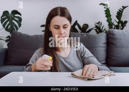 Close up of young caucasian woman tidy housewife cleaning white wooden table in living room at home. Happy brunette female cleaning service worker wip Stock Photo