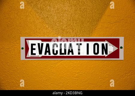 Evacuation Sign- hobbled together from some other kind of sign and stick on letters - tacked to orange stucco wall. Stock Photo