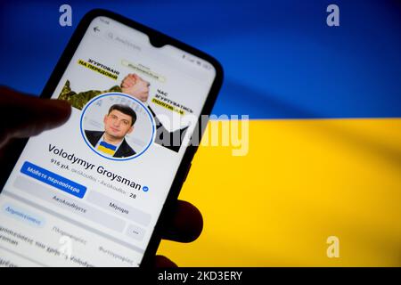 In this photo illustration Volodymyr Zelenskyy Facebook page seen displayed on a smartphone screen with a flag of Ukraine on computer screen in the background in Athens, Greece on February 25, 2022. (Photo illustration by Nikolas Kokovlis/NurPhoto) Stock Photo