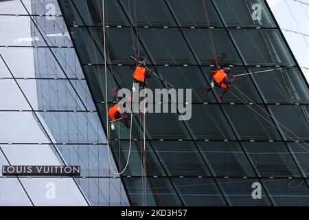 Workers clean the all-glass structure of the Louis Vuitton Marina Bay store facade on February 26, 2022 in Singapore. (Photo by Suhaimi Abdullah/NurPhoto) Stock Photo