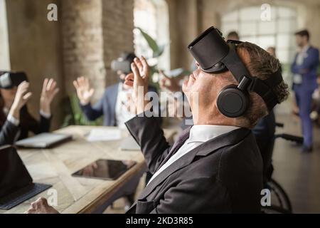 Cyberspace experience at work. Group of office workers wearing VR goggles, looking at objects in digital world, focus on businessman in 3d glasses int Stock Photo