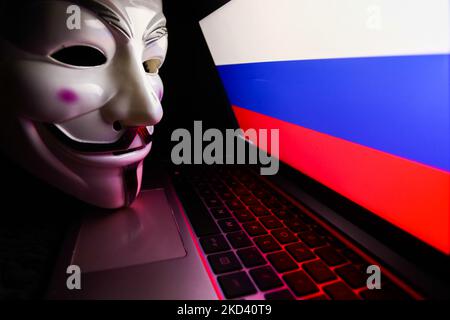 Russian flag displayed on a laptop screen and Guy Fawkes mask are seen in this illustration photo taken in Krakow, Poland on March 1, 2022. Global hacker group Anonymous declared 'cyber war' against Russia. (Photo by Jakub Porzycki/NurPhoto) Stock Photo