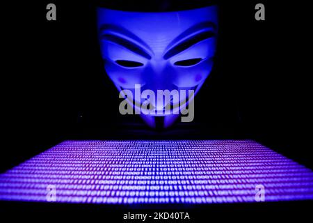 Binary code displayed on a laptop screen and Guy Fawkes mask are seen in this illustration photo taken in Krakow, Poland on March 1, 2022. Global hacker group Anonymous declared 'cyber war' against Russia. (Photo by Jakub Porzycki/NurPhoto) Stock Photo