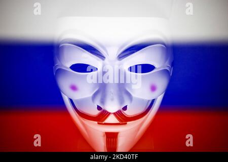 Russian flag displayed on a laptop screen and Guy Fawkes mask are seen in this multiple exposure illustration photo taken in Krakow, Poland on March 1, 2022. Global hacker group Anonymous declared 'cyber war' against Russia. (Photo by Jakub Porzycki/NurPhoto) Stock Photo