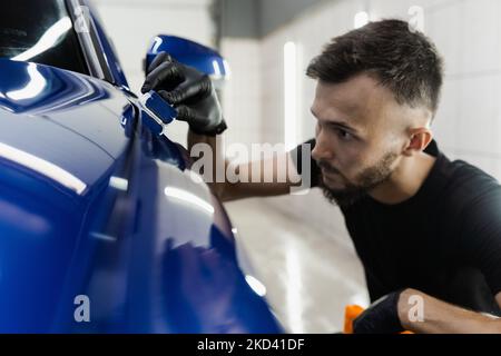 Detailing service worker applies ceramic protective liquid on car. Hand applying of nano ceramic protective coat to protect car from scratches Stock Photo