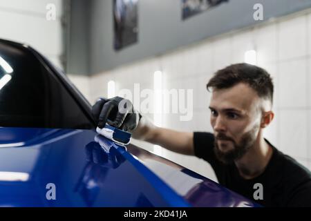 Detailing service worker applies ceramic protective liquid on car. Hand applying of nano ceramic protective coat to protect car from scratches Stock Photo