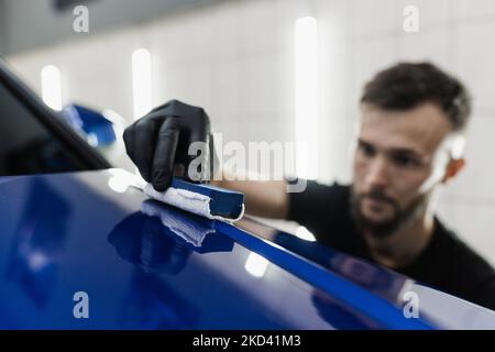 Detailing service worker applies ceramic protective liquid on car. Hand applying of nano ceramic protective coat to protect car from scratches Stock Photo