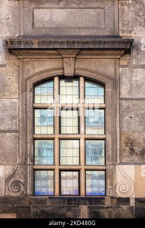 Rectangular cellular arched window with opaque glass against the background of an old weathered stone wall of brown color. From the Windows of the wor Stock Photo