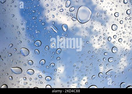 Sky and Clouds through large raindrops on window background Stock Photo