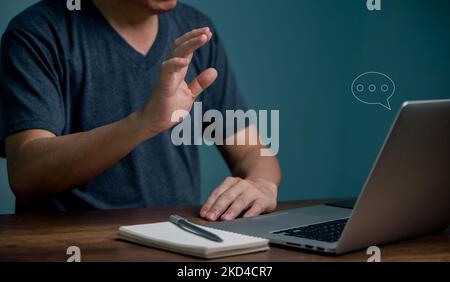 Young man learning online class and meeting online by using laptop computer and writing on notebook, E-learning and online communication concept. Stock Photo