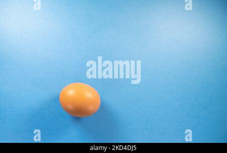 a single brown hens egg isolated on a dark blue background Stock Photo