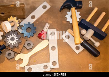 Toy wooden toy tools including gears and a wrench and hammer scattered on a wooden surface - top lay Stock Photo