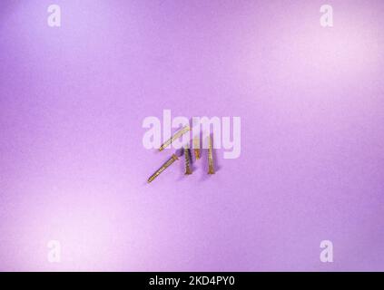 five used and rusted screws isolated on a purple background Stock Photo