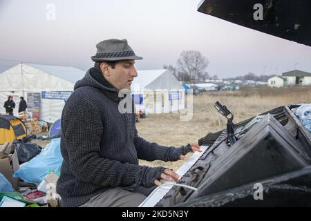 German pianist of Italian descent Davide Martello known as Klavierkunst performs in Medyka, at the Ukrainian Polish border crossing of Medyka Shehyni. The musician, an artist plays grand piano near the Ukrainian border for the arriving war refugees from Ukraine in front of the tents and the buses that get them to relocate. Thousands of civilian refugees cross the Ukrainian-Polish border daily due to the Russian invasion of Ukraine. Medyka, Poland on March 14, 2022 (Photo by Nicolas Economou/NurPhoto) Stock Photo