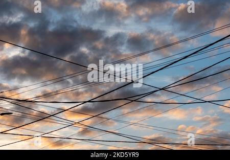 Messy numerous wires on background of gloomy dark sky on sunset Stock Photo