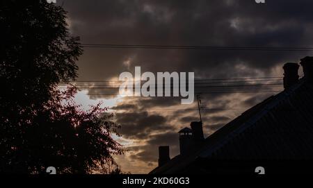 Silhouettes of trees and houses against background of gloomy dark sky Stock Photo
