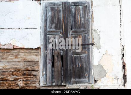 Dilapidated wooden window shutters of old abandoned house on white wall Stock Photo