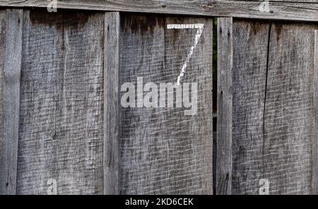 Fence made of rough old unpainted wooden boards with the number 7 painted on it. Vertical arrangement Stock Photo