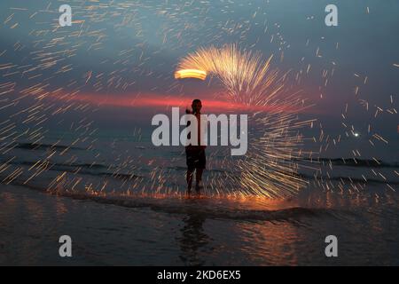 A Palestinian swings fireworks , as people celebrate on the night ahead of the Muslim holy fasting month of Ramadan, on the beach of Gaza City, on April 1, 2022. (Photo by Majdi Fathi/NurPhoto) Stock Photo