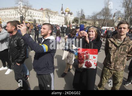 Ukrainians attend April Fools' Day concert, amid Russia's invasion of Ukraine, in the city of Odesa, Ukraine on 1 April 2022. The musical concert “Odesa goes into battle without drama” was held at the entrance to the railway station to cheer up locals and residents of other regions of the country who are evacuating to the city. People walk next to a mock-up of the improvised light 'Odesa tank', which was produced by local enterprises during the siege of Odesa during the Second World War of 1941. (Photo by STR/NurPhoto) Stock Photo