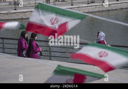 Iranian women stand behind Iran flags in the Art Museum Garden in northern Tehran during a ceremony to mark Iran’s Islamic Republic National day on April 1, 2022. Iranian people voted yes in a referendum for the Islamic Republic regime forty three years ago. (Photo by Morteza Nikoubazl/NurPhoto) Stock Photo