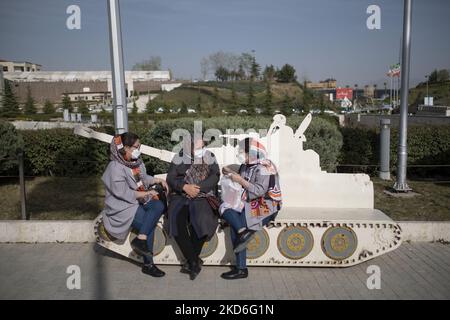 Iranian women sit on a bench with a shape of a military tank out of the Revolution and holy defense museum in northern Tehran during a ceremony to mark Iran’s Islamic Republic National day on April 1, 2022. Iranian people voted yes in a referendum for the Islamic Republic regime forty three years ago. (Photo by Morteza Nikoubazl/NurPhoto) Stock Photo
