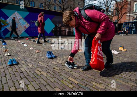 A Ukrainian woman is putting children's shoes on the floor, as a part of a Ukrainian art installation to draw attention to the killings of civilians and in particular children during the war in Ukraine. The Hague, on April 2nd, 2022. (Photo by Romy Arroyo Fernandez/NurPhoto) Stock Photo