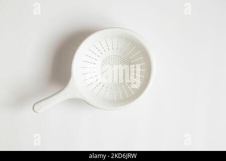 Colander white plastic lies on a white background close-up Stock Photo