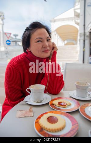 Close-up of a beautiful asian woman with red cloth sitting at a bar having breakfast. Stock Photo