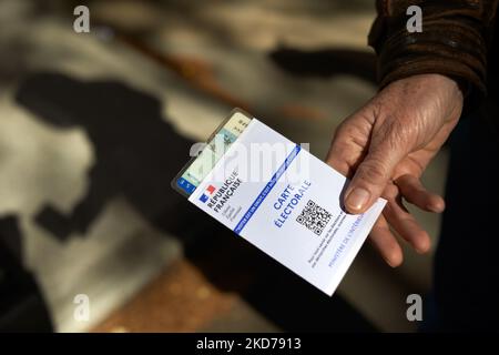 A woman shows her poll card with an ID before going to the polls. For the first round of the French presidential election, people go to the polling station. Even if pollsters said that abstention will be around 30% (a record for a presidential election), assessors of the polling station said more people came to cast their ballot than in 2017. Twelve candidates are running for the election including Emmanuel Macron, currently in office. Toulouse. France. April 10th 2022. (Photo by Alain Pitton/NurPhoto) Stock Photo