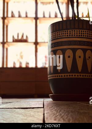 A vertical selective shot of painted patterns on a clay pot for plants on floor Stock Photo