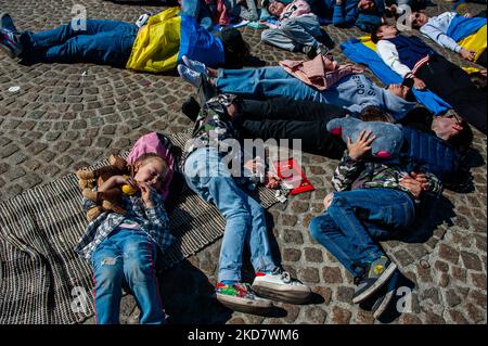 A Ukrainian family lie on the ground in front of the Dam square in Amsterdam, to protest Russia’s war in Ukraine, on April 17th, 2022. (Photo by Romy Arroyo Fernandez/NurPhoto) Stock Photo